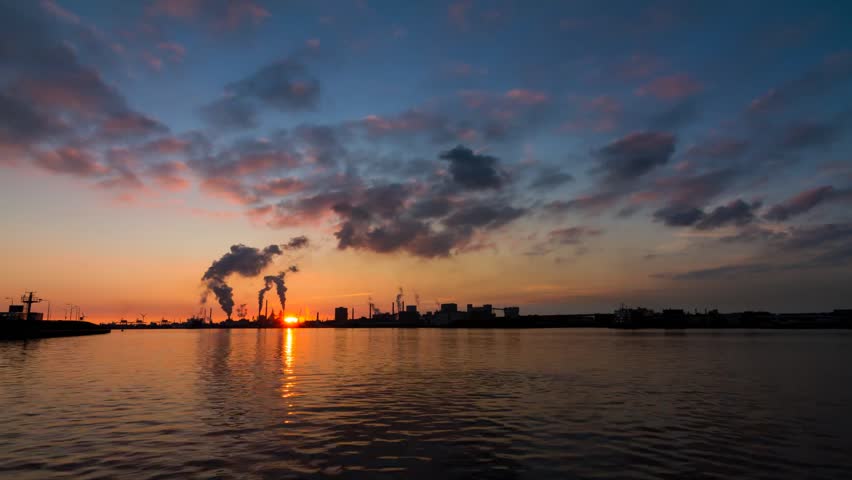 Beautiful full HD time lapse of heavy industry with smoking chimneys and cargo ships along a waterway in IJmuiden, the Netherlands. 