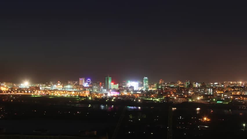 City across the river from the bridge on which cars are traveling at night