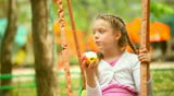 Little girl eating an apple on a swing 