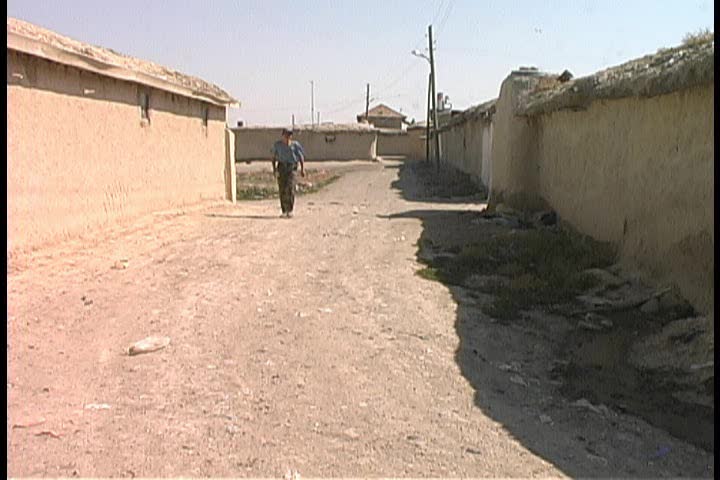 A young villager walking down a road in a mud village