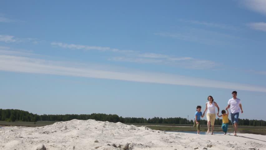 Family of four runs on sand 