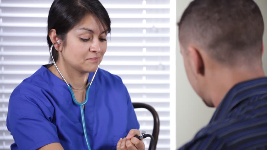 A lovely Hispanic nurse taking a male patientÃÂ¢??s blood pressure.
