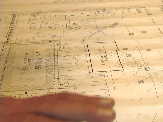 CLOSE-UP OF AN ARCHITECT POINTING OUT IMPORTANT AREAS OF A BLUEPRINT.