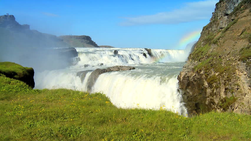 Concept shot of two people by a glacial waterfall using umbrellas to shelter from the economic & environmental climate 60 FPS