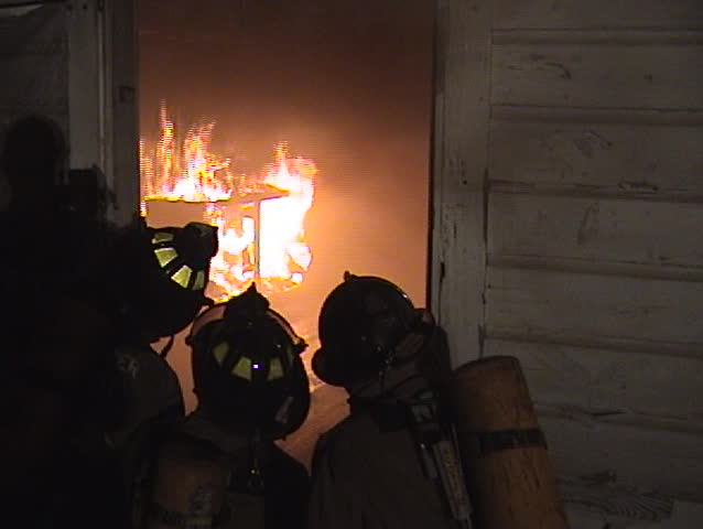 Firemen look inside the door at the fire during a training burn.