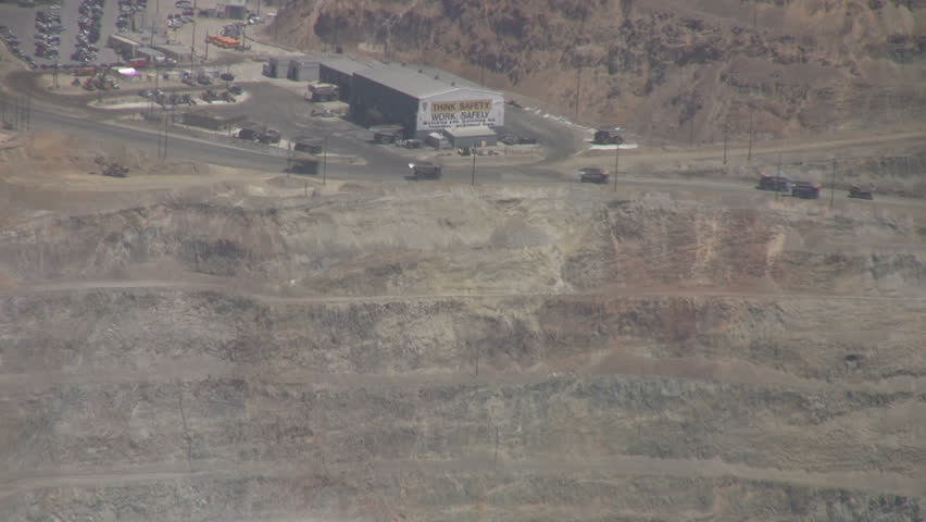 Video Kennecott Copper Mine central Utah. Zoom out trucks to pit. Ophir Mountains near Salt Lake City. Mountain top forest around open pit mine.  Don Despain of Rekindle Photo.