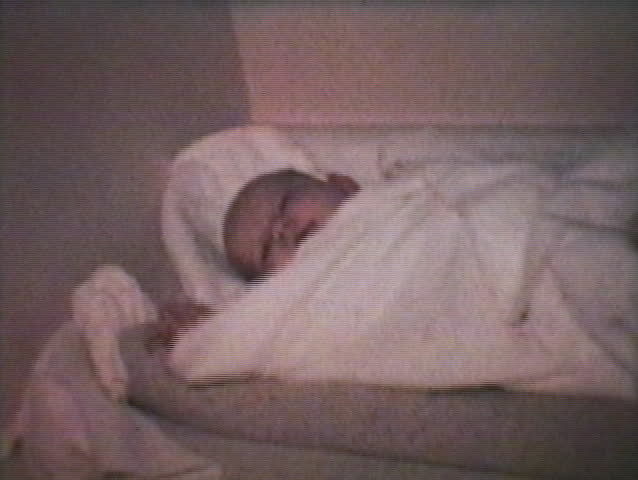 A happy baby girl resting contentedly wrapped in her cozy blanket. (1968 - Vintage 8mm film)