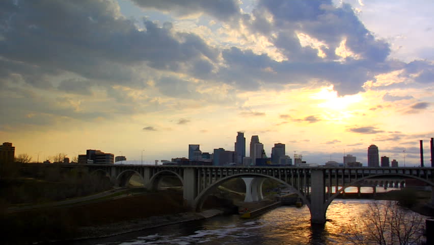 An awe inspiring timelapse shot of downtown Minneapolis, MN.  The colors are golden and the two systems of clouds are moving in opposite directions. 