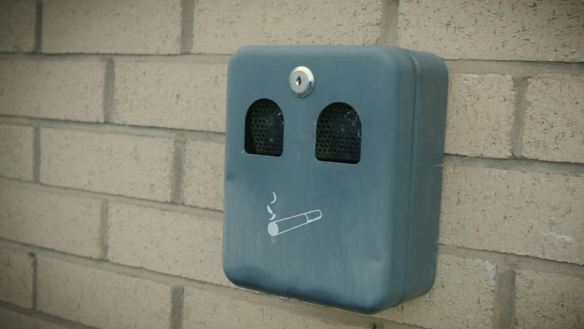 stubbing cigarette out into an exterior ashtray.