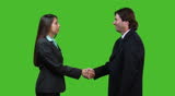 Businesswoman is shaking hands with a businessman then turning towards camera - green screen