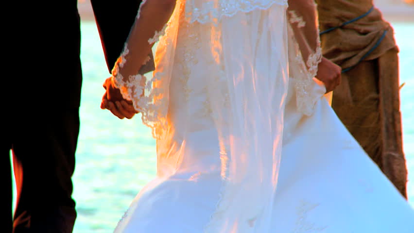 Young couple walking beach side  after their tropical wedding ceremony