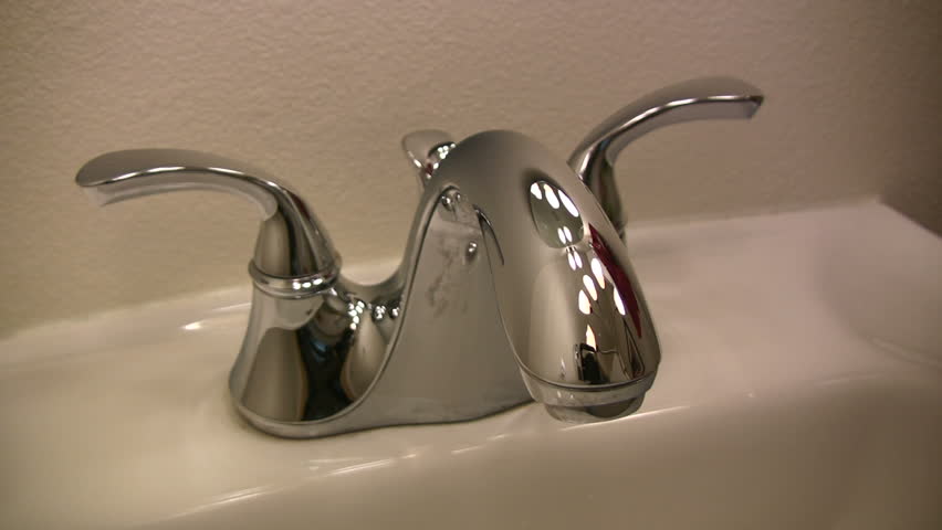 HD 1080i shot of a sink faucet being turned on the back off.