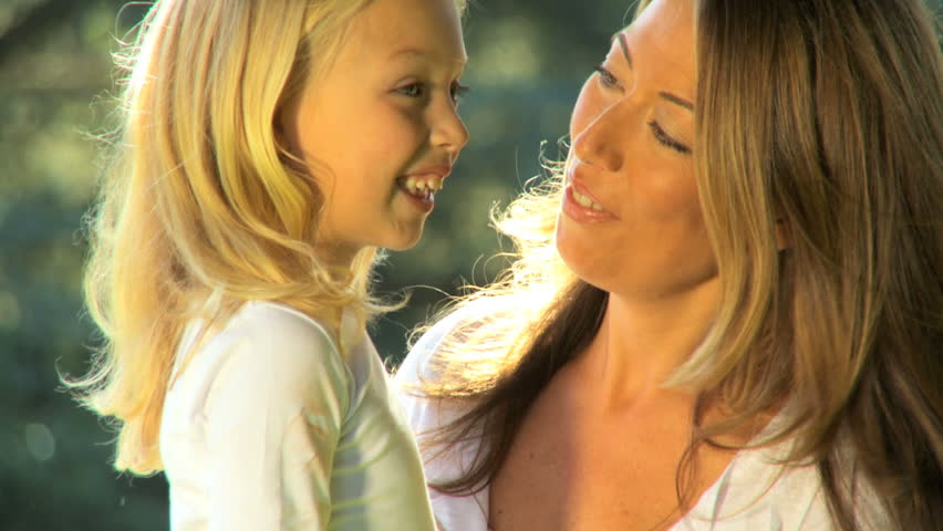 Attractive mother tenderly holding her daughter while outdoors on a summers day