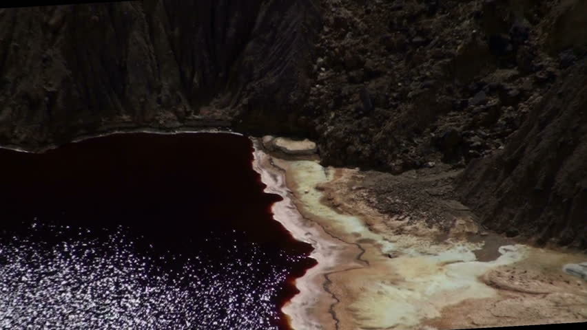 Mine pit zoom out reveals sparkling reflection dancing on stagnant pool surface. 1920x1080