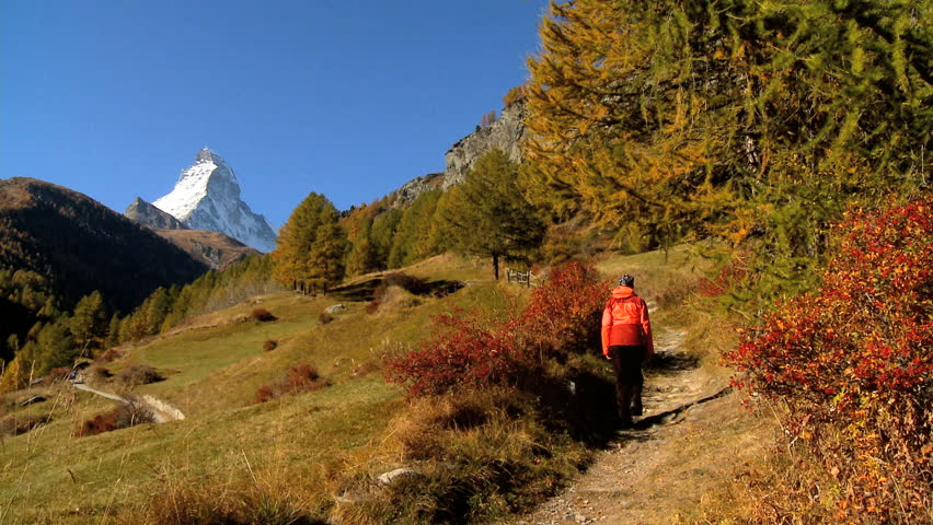 Fall in an alpine meadow, Zermatt, with female hiker & the Matterhorn, motion jib