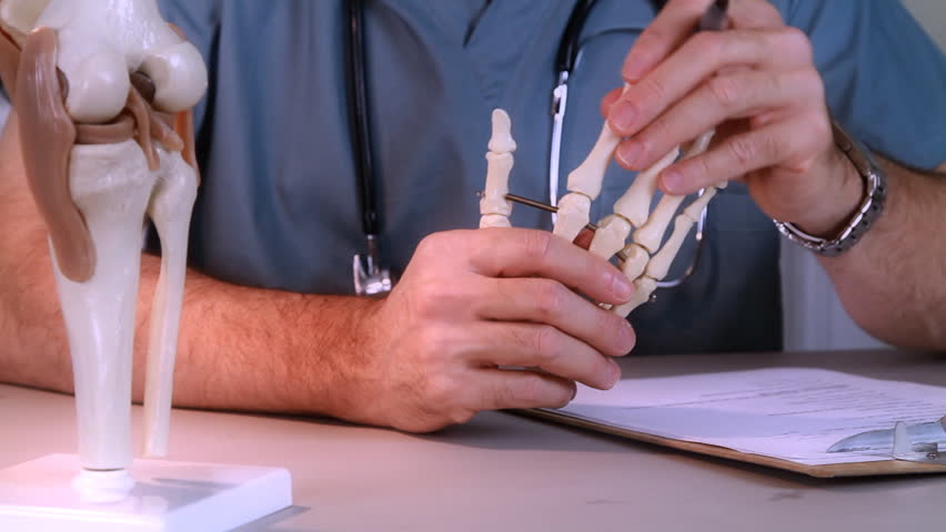 A doctor or intern studying a skeletal model of the human hand.