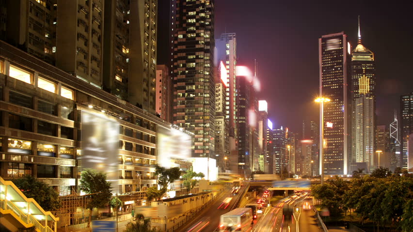 Hong Kong cityscape timelapse at night. With busy traffic across the main road at rush hour.