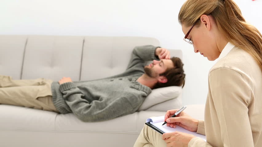 Young Man Lying On Sofa Talking To His Therapist At Therapy Session