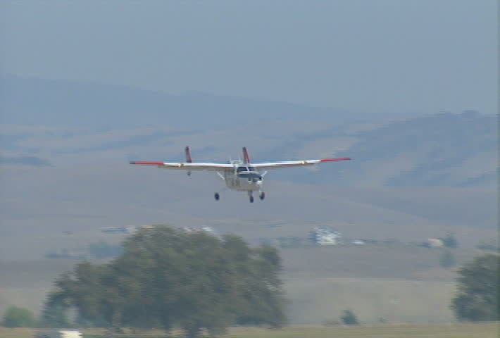 A small plane touches down on the tarmac at an airstrip. 