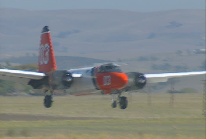 A fixed-wing patrol aircraft touches down on the tarmac of an airstrip.