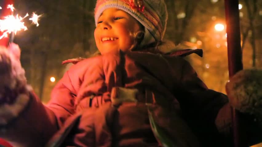 little girl teetering and holding sparkler in hand, night outdoor 