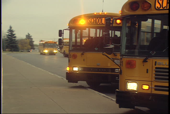 rack focus of school buses lining up to drop off kids