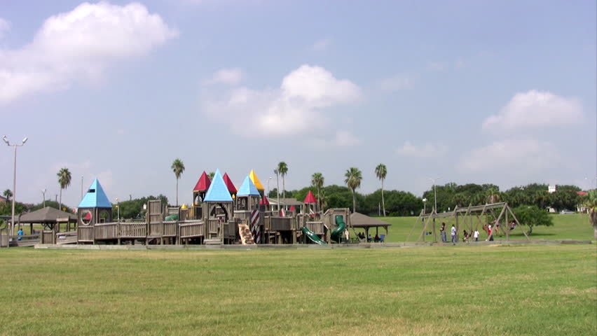 Video of playground wood castle structure and swing set with kids or children park. Oversize jungle jim with buildings, bridges and walks in a city park. Kids activity and recreation. 