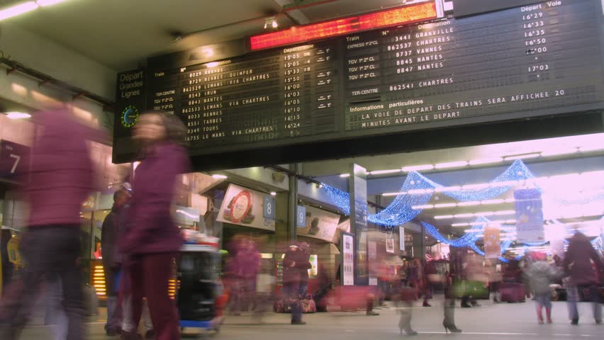 Board with departure of trains, passengers in a station building in Paris, France. Time lapse. 