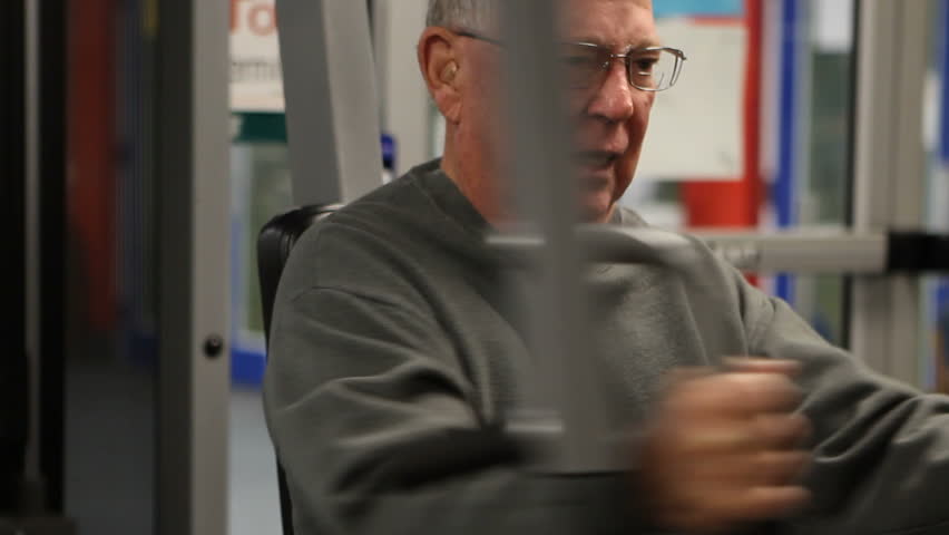 Elderly man does a chest muscle workout at the fitness club.
