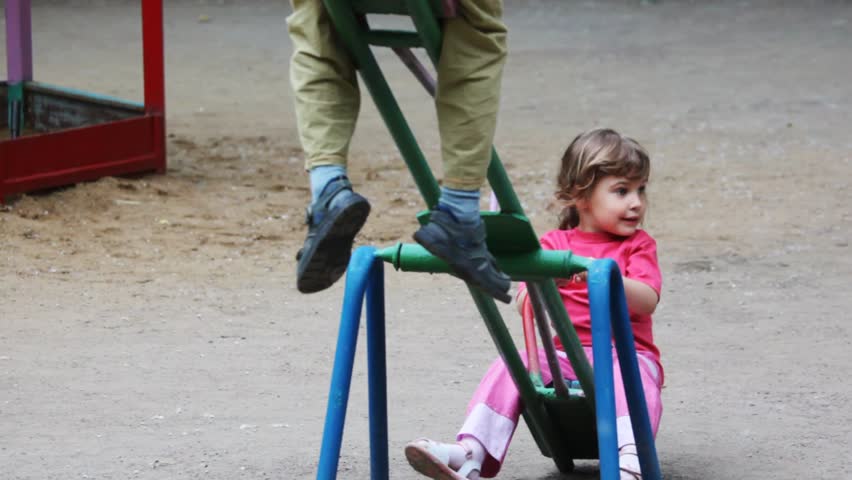 boy and girl play at seesaw together on playground 