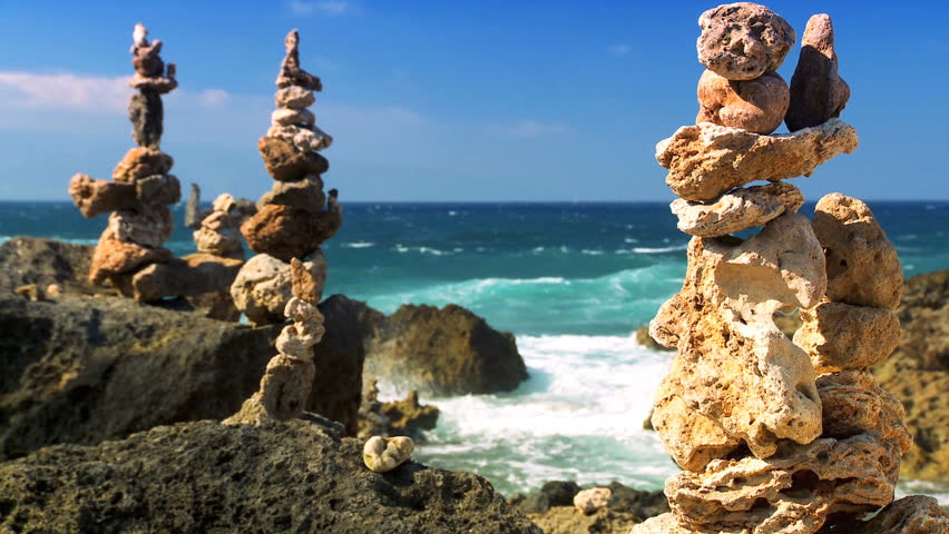 Small rocks symmetrically balanced in peaceful location on shoreline with ocean backdrop