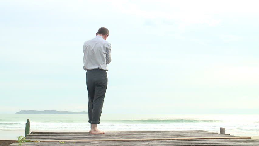 HD 1080i: Depressed barefoot businessman walking at the sea.