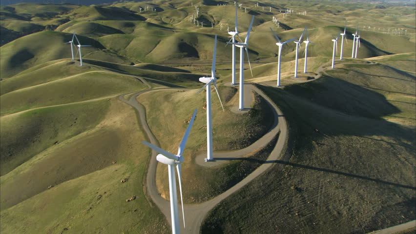 Low aerial view of cluster of wind turbines in green hillside