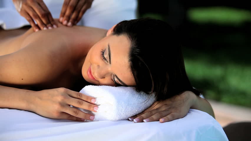 Beautiful young brunette girl relaxing with massage treatment at the health & beauty spa