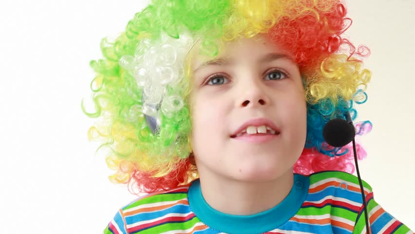 Boy in headset and ridiculous multicolor wig shakes his head and sings 