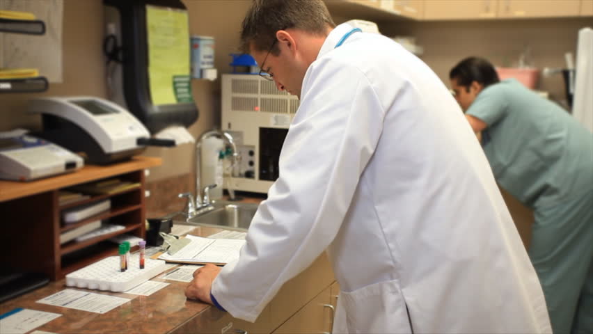 A doctor and a nurse or technician working in a clinics small laboratory.