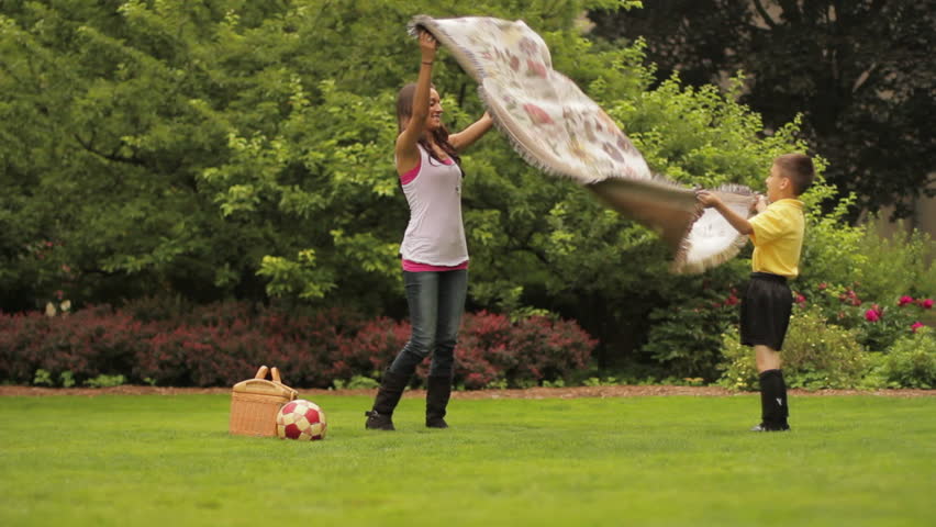 Mother and son set spread out a blanket for a picnic