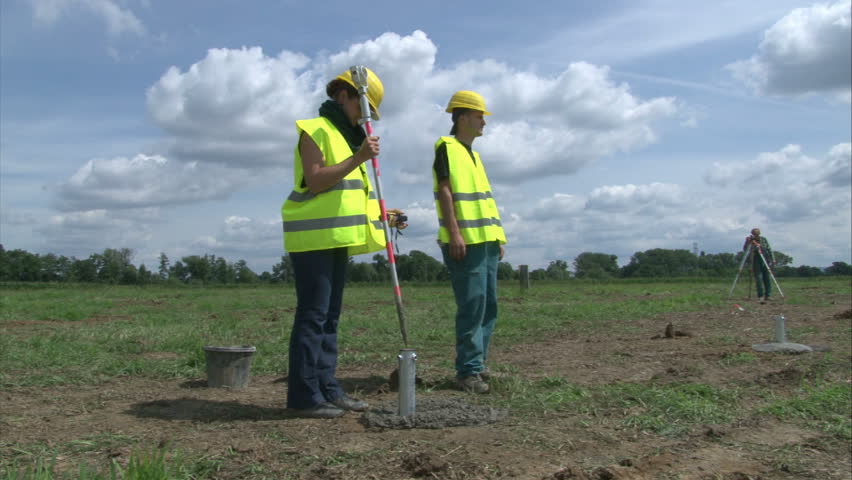 Geodesist with workers are adjusting pillar in cement for solar power plant construction. 