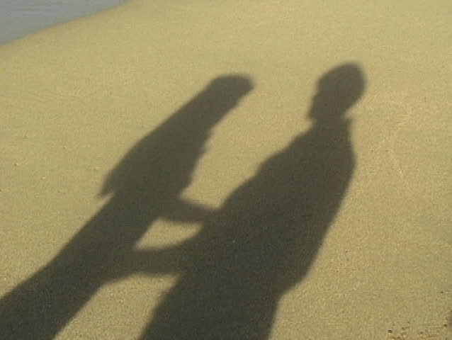 Shadow on beach of two lovers kissing