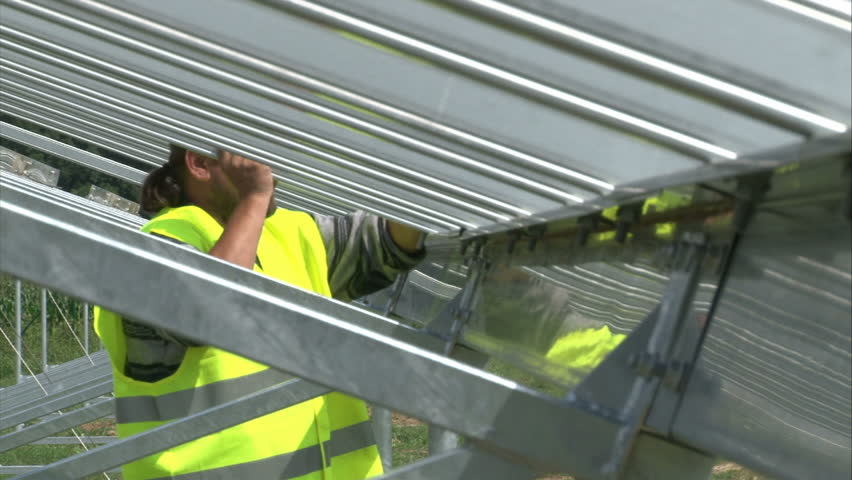 Worker is tightening up nut on metal solar power-plant construction.