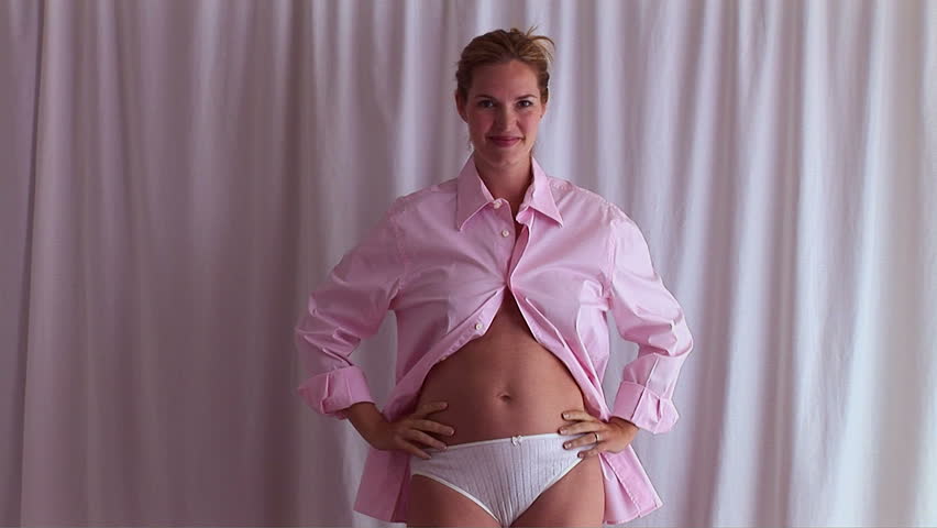 Pregnant woman posing in man's pink shirt