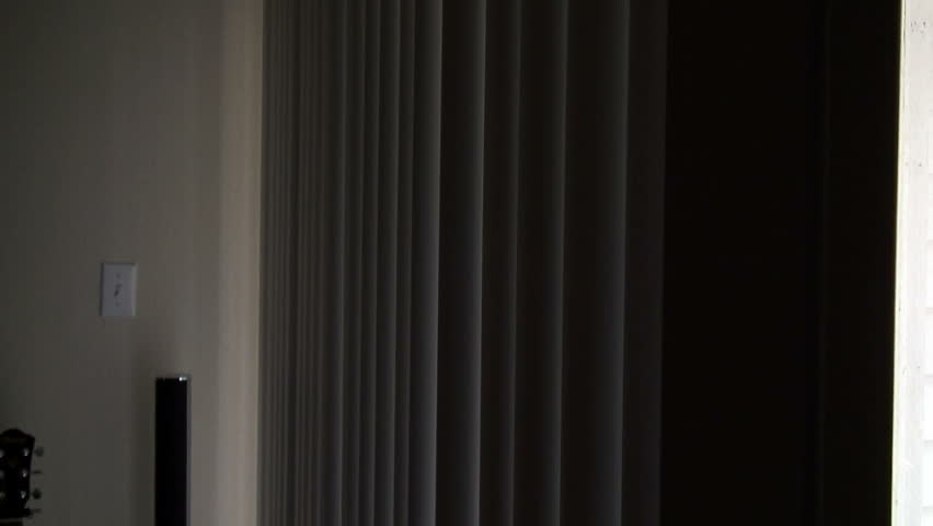 Apprehensive woman looks out of the window as she hears a strange noise