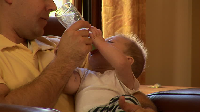 Young father feeding baby son bottle of milk at Christmas time