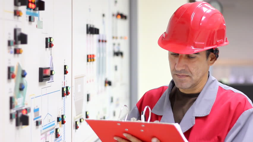 Engineer standing in front of the control panel in the control room and write the results of the measurements.