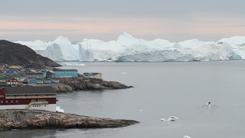 A small boat leaving the harbor in Ilulissat, Greenland for the ice-fjord in the background. 