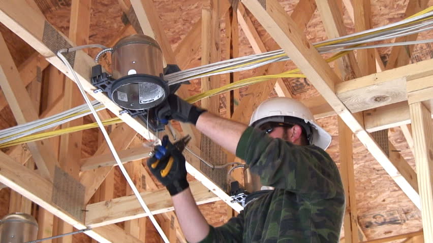 New home construction, electrician installing a ceiling light. Ambient audio included.
