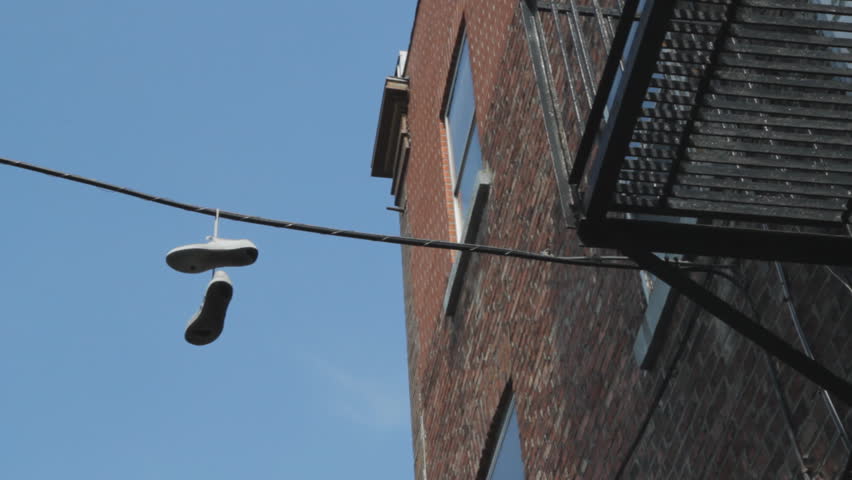 Sneakers hanging from wire. A pair of sneakers hanging from an overhead wire. Apartments nearby. Montreal, Quebec, Canada. 