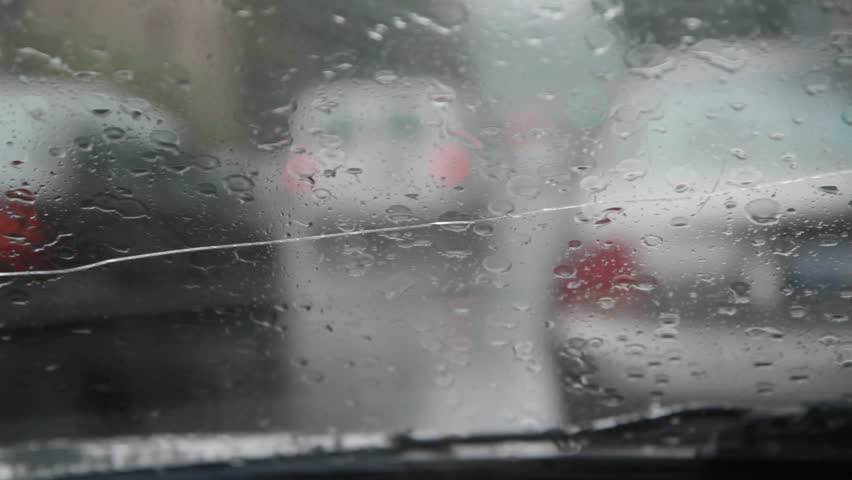 Rainy traffic. Cracked windshield. Looking through a cracked windshield at defocused traffic. Sound of heavy rain falling and squeaky wipers. 