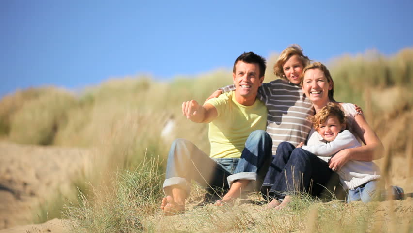 Attractive young caucasian family enjoying leisure time together on coastal sand dunes