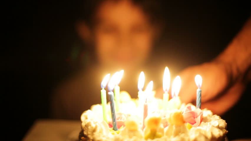 Boy claps and blows out candles on birthday cake. 